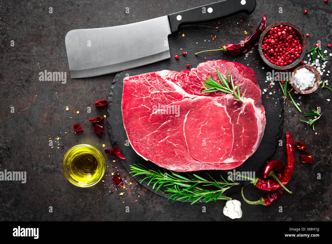 Steak de boeuf cru sur fond noir avec des ingrédients. La viande de boeuf fraîche. Vue d'en haut Banque D'Images