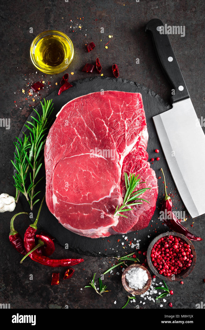 Steak de boeuf cru sur fond noir avec des ingrédients. La viande de boeuf fraîche. Vue d'en haut Banque D'Images