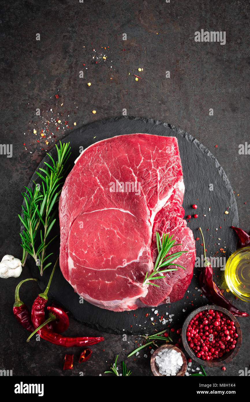 Steak de boeuf cru sur fond noir avec des ingrédients. La viande de boeuf fraîche. Vue d'en haut Banque D'Images
