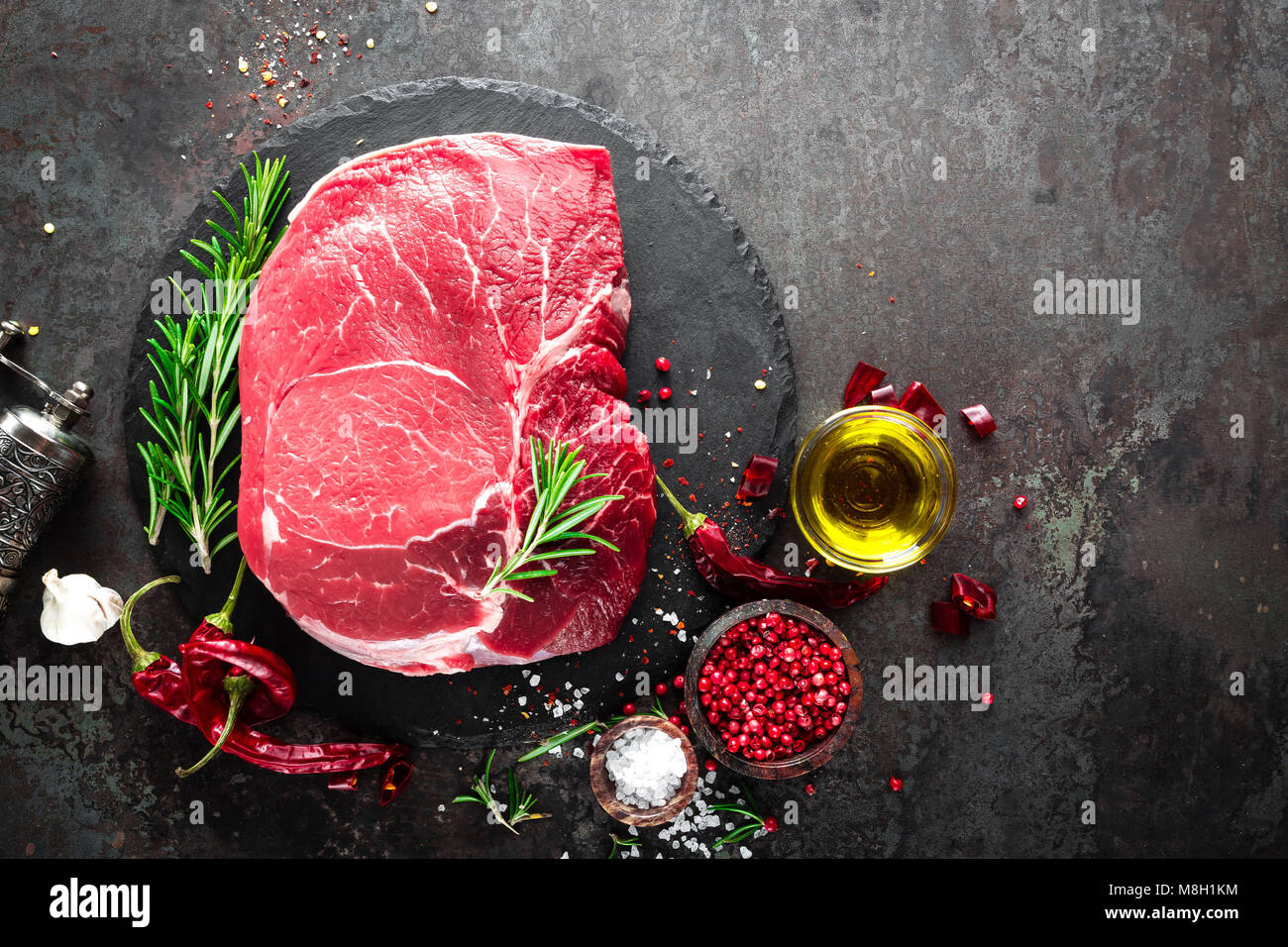 Steak de boeuf cru sur fond noir avec des ingrédients. La viande de boeuf fraîche. Vue d'en haut Banque D'Images