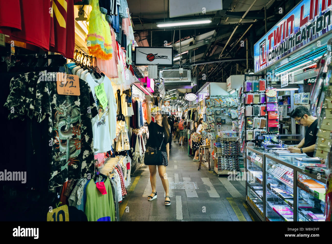 Singapour, Bugis Street. Parmi des centaines de magasins de vêtements, accessoires et budget gadgets, un des points de l'acheteur à quelque chose qui a attiré son attention. Banque D'Images