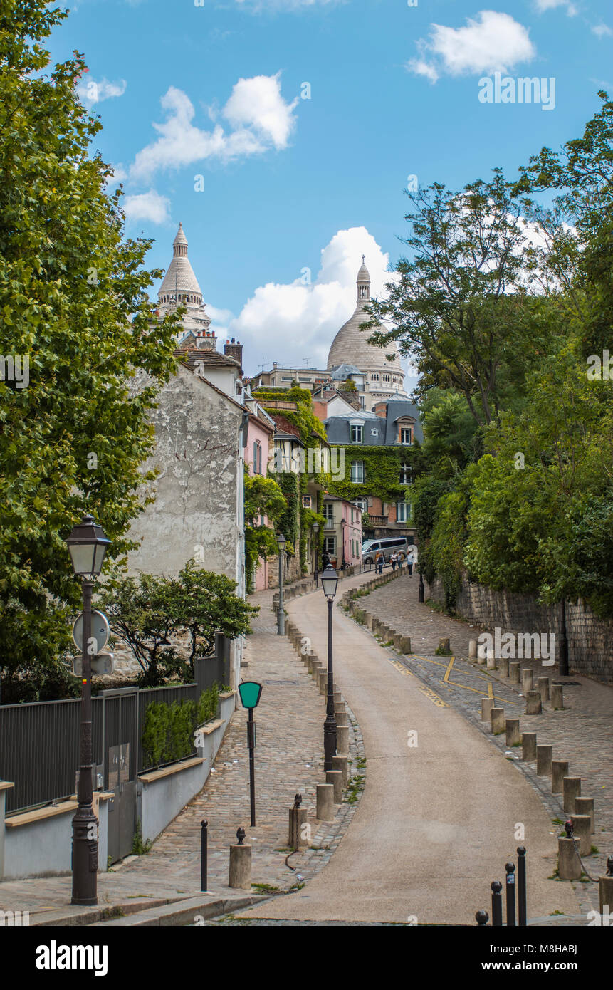 Vue de la route sinueuse s'enfuir entre les trottoirs pavés et vert des arbres sur rue avec l'architecture ancienne à Paris, France Banque D'Images
