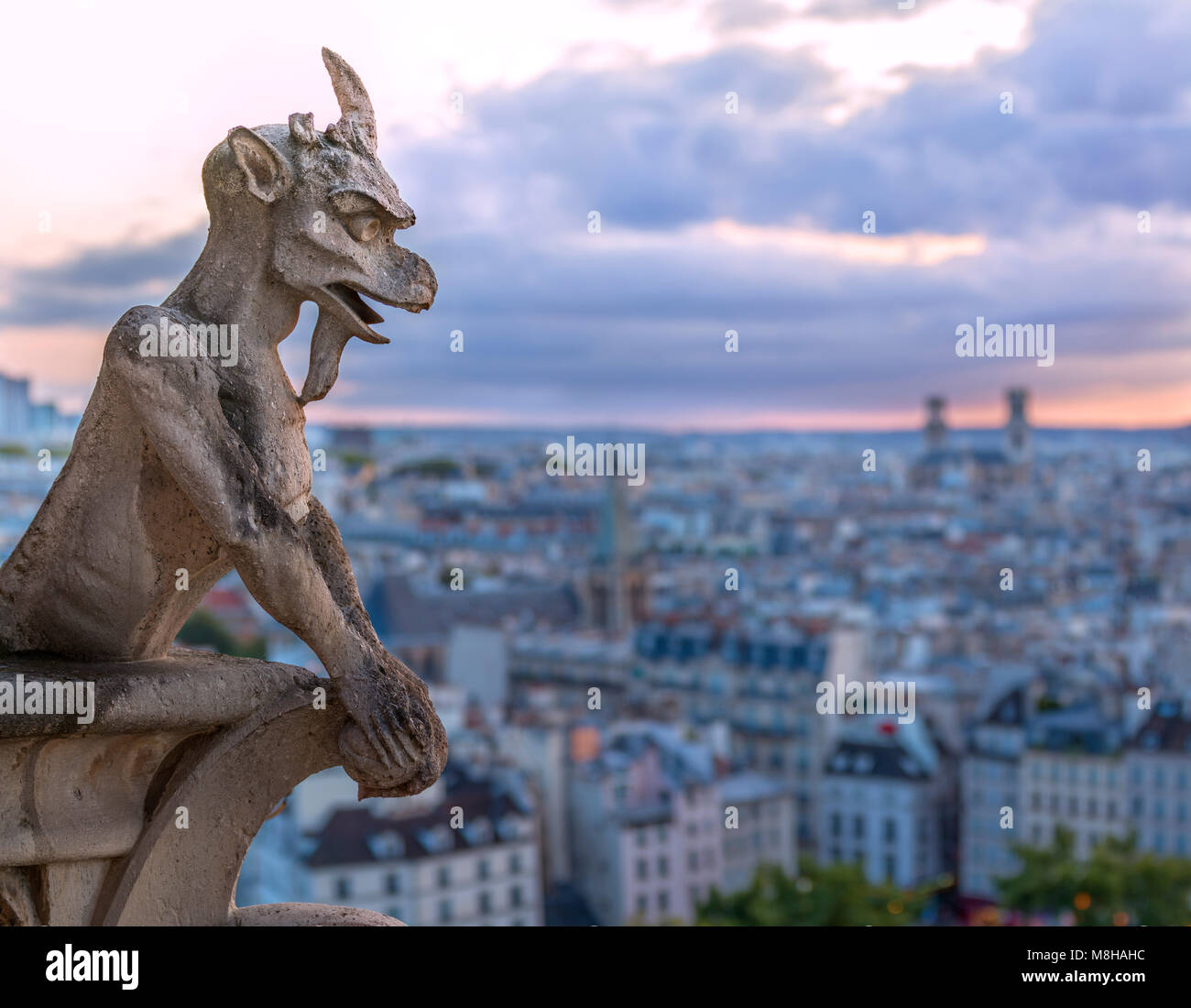 Shabby statue en pierre de gargoyle dans notre-dame cathédrale avec arrière-plan de Paris dans la ville lumière au coucher du soleil Banque D'Images