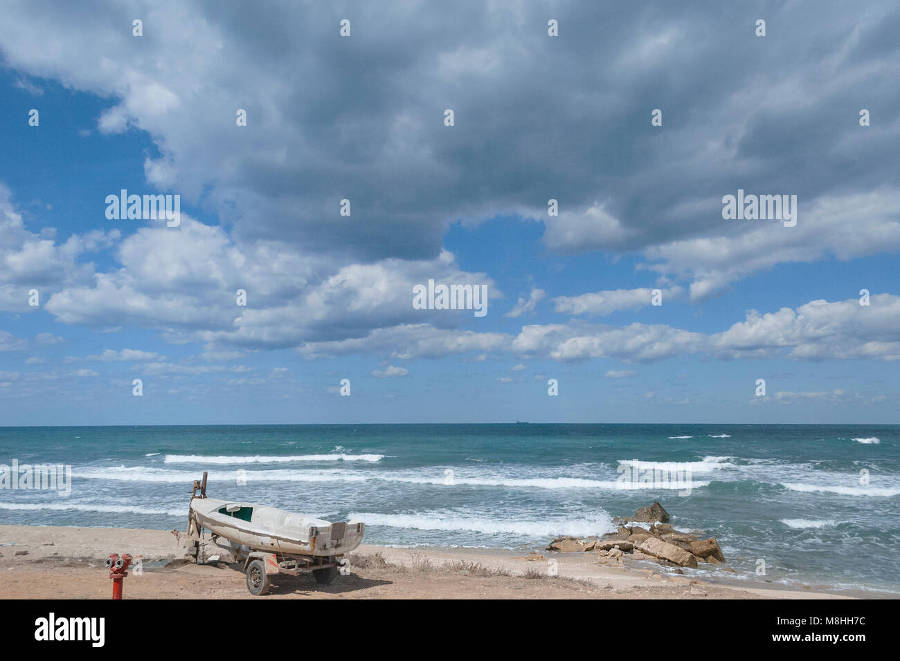 Paysage marin méditerranéen avec petit bateau et des roches sous un ciel d'orage Banque D'Images