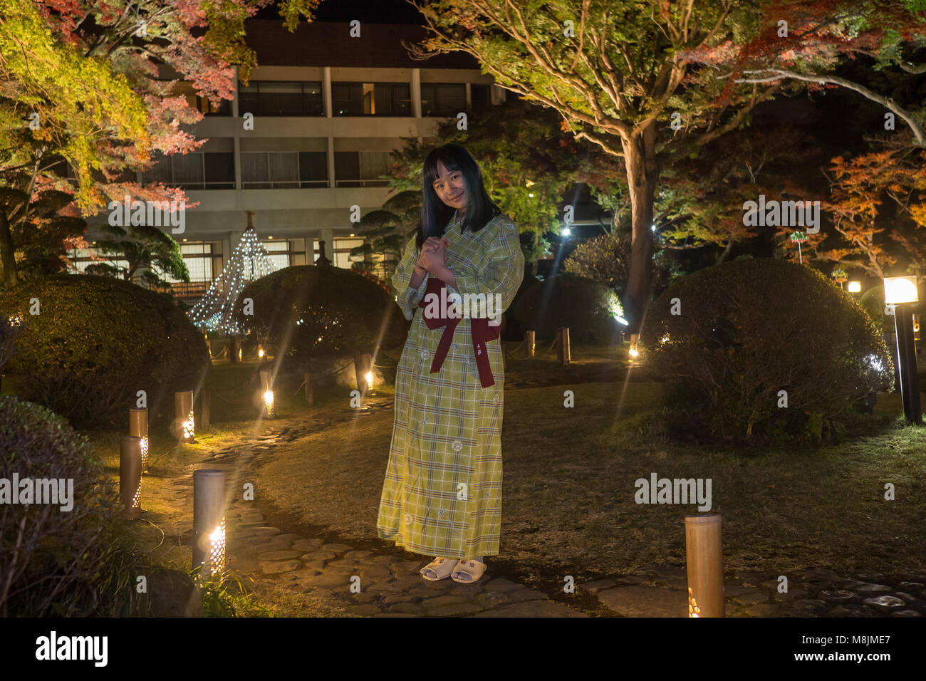 Belle jeune femme dans un yukata se promenant dans un jardin japonais Banque D'Images