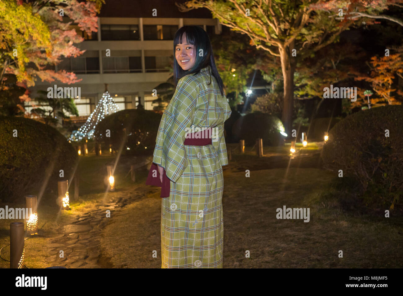 Belle jeune femme dans un yukata se promenant dans un jardin japonais Banque D'Images