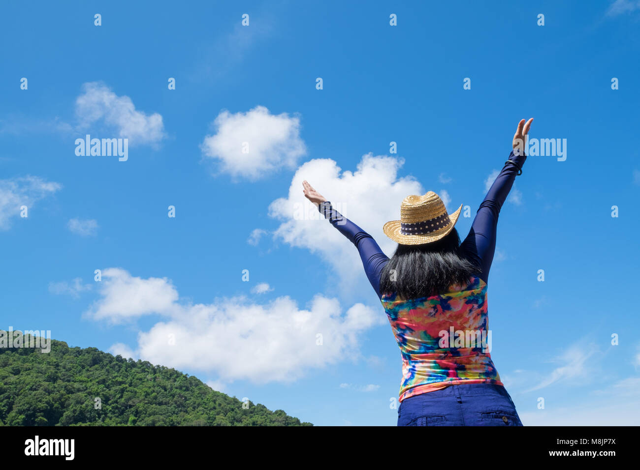 Traveller femme avec maillot coloré les bras levés au ciel en haut de montagne avec bonheur moment,les vacances d'été en voyage. Banque D'Images