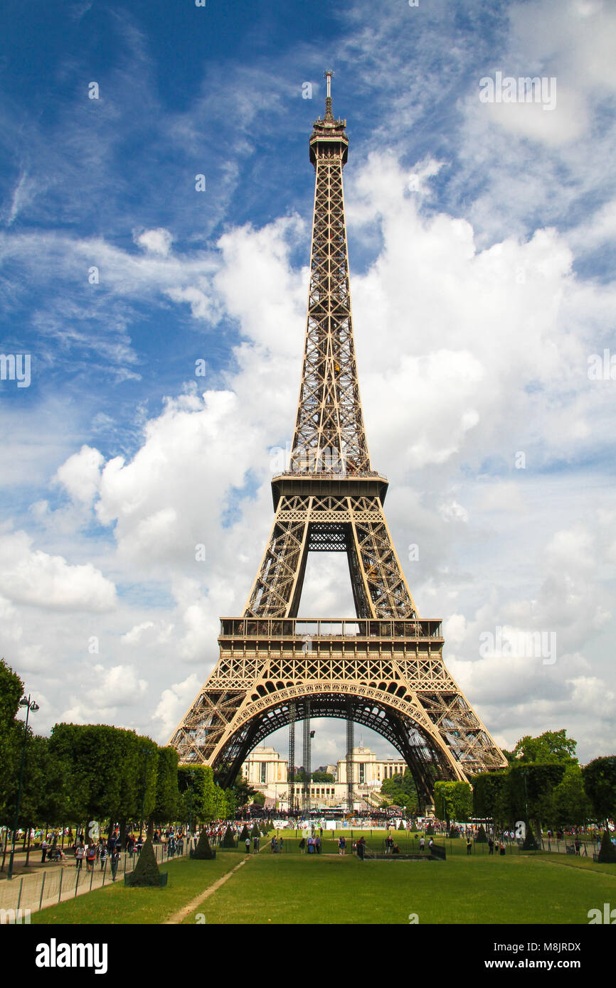 Un trait vertical, pleine longueur sur la Tour Eiffel à Paris, France à la golden dans l'été avec ciel bleu et nuages blancs. Banque D'Images