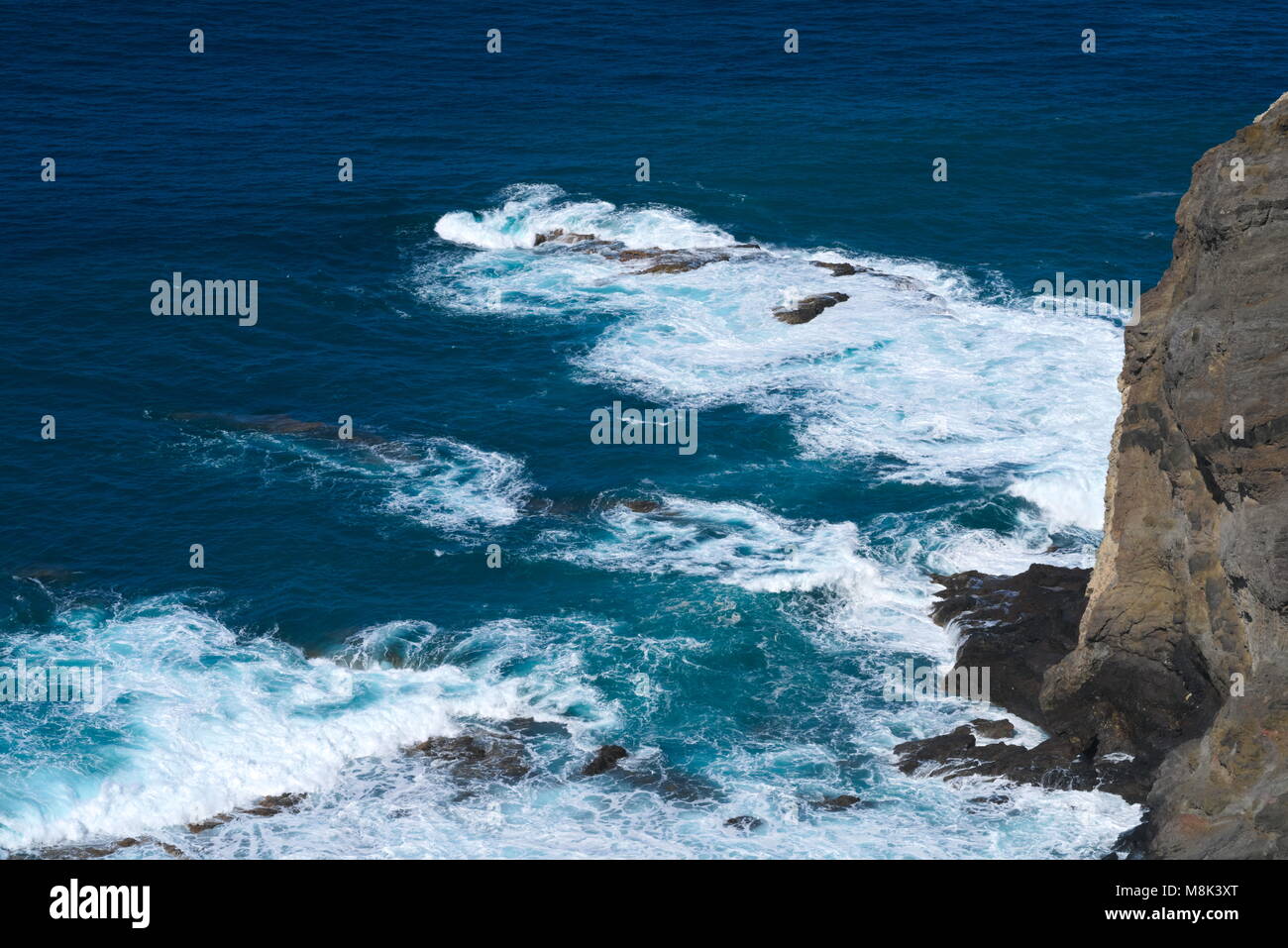 L'océan bleu avec blanc des vagues à une falaise au-dessus de la côte Banque D'Images