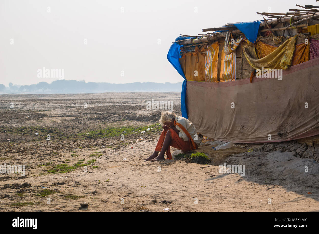 VARANASI, Inde. 28 février 2017 : l'ermite, un sadhu, est assis en méditant sur l'opposé de l'Varanasi rives du fleuve saint Ganges Banque D'Images