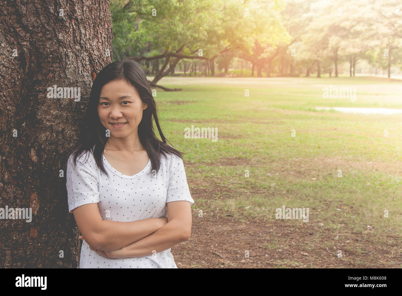 Maison de vacances et de Concept : Woman wearing white t-shirt. Elle debout sur l'herbe verte et le sentiment de bonheur et vous détendre dans le parc. Banque D'Images