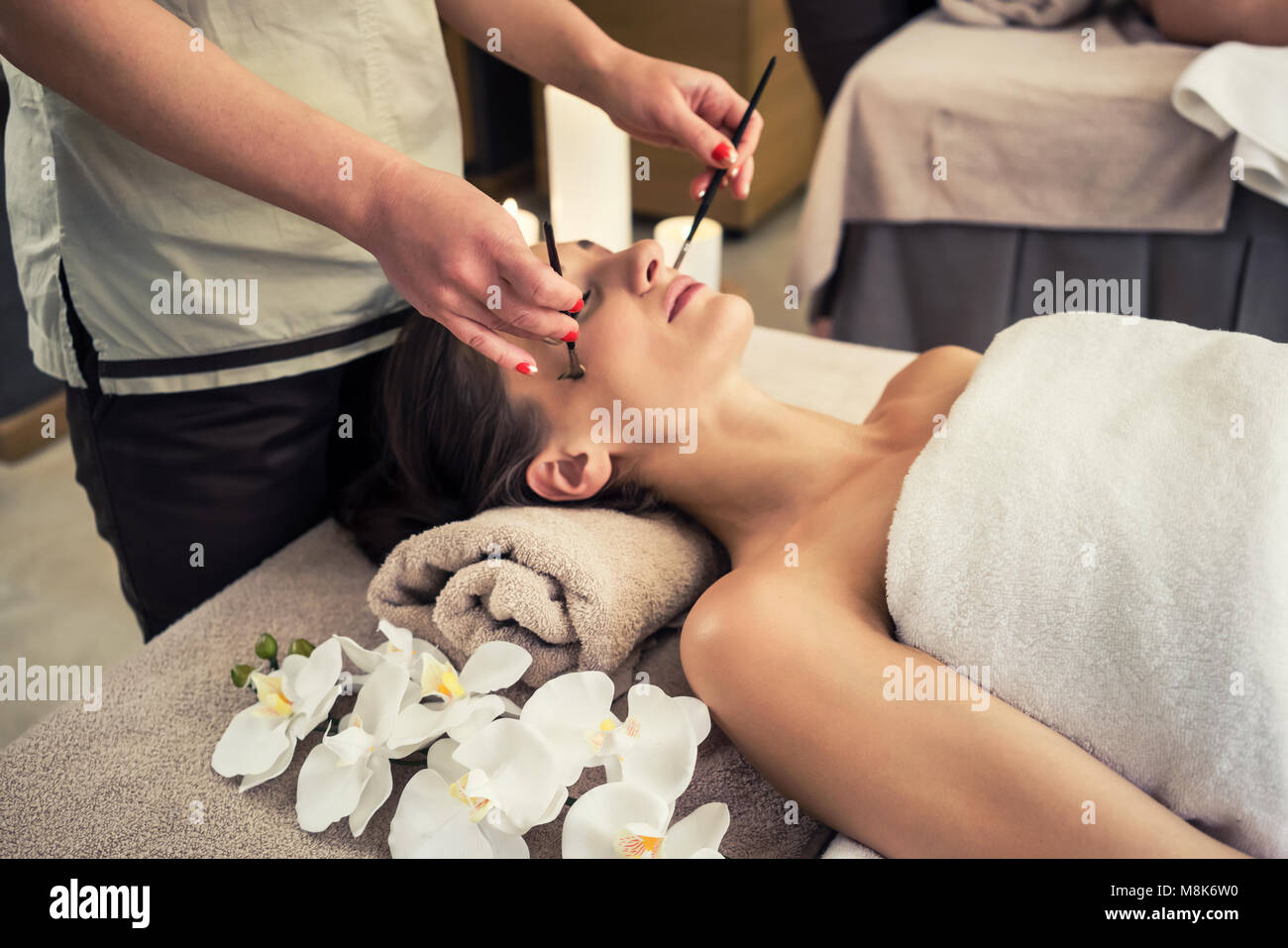 Femme couchée détendue sur lit de massage au cours de traitement du visage Banque D'Images