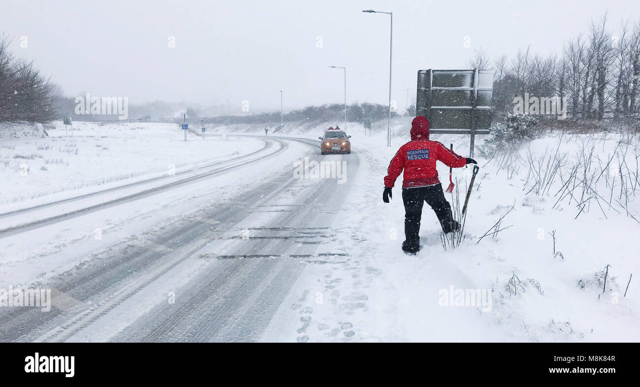 Membre de l'équipe de recherche et de sauvetage Dartmoor montres un automobiliste roulant le long d'une route près de Okehampton Devon comme beaucoup de neige a apporté le chaos de la circulation à certaines parties du sud-ouest. Banque D'Images