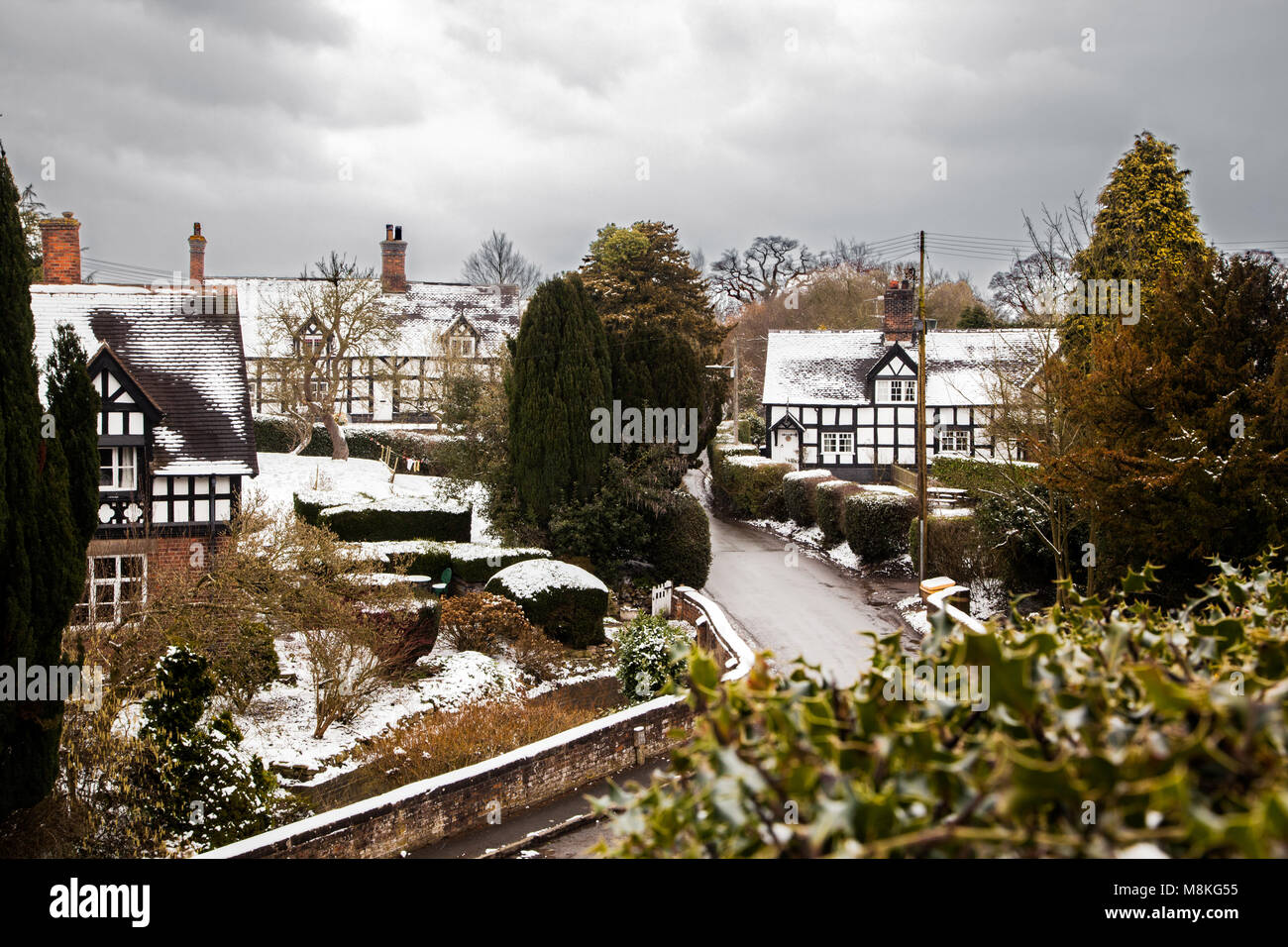 Noir et blanc couvert de neige maisons à colombages dans le pittoresque village de Barthomley Cheshire England UK en hiver Banque D'Images