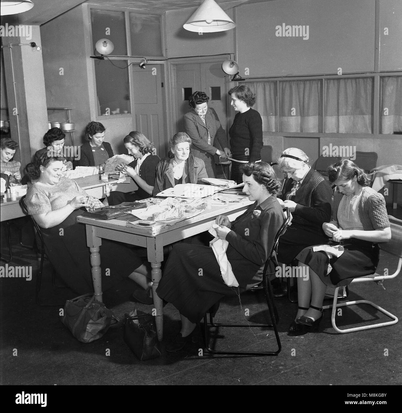 Années 1950, tableau historique des femmes à un groupe de couture ou de couture, England, UK pendant et après la guerre, en Grande-Bretagne, en faisant vos propres vêtements et autres articles textiles d'activité des femmes a été très populaire, avec de nombreux magazines, brochures et les classes disponibles pour l'encourager. Banque D'Images