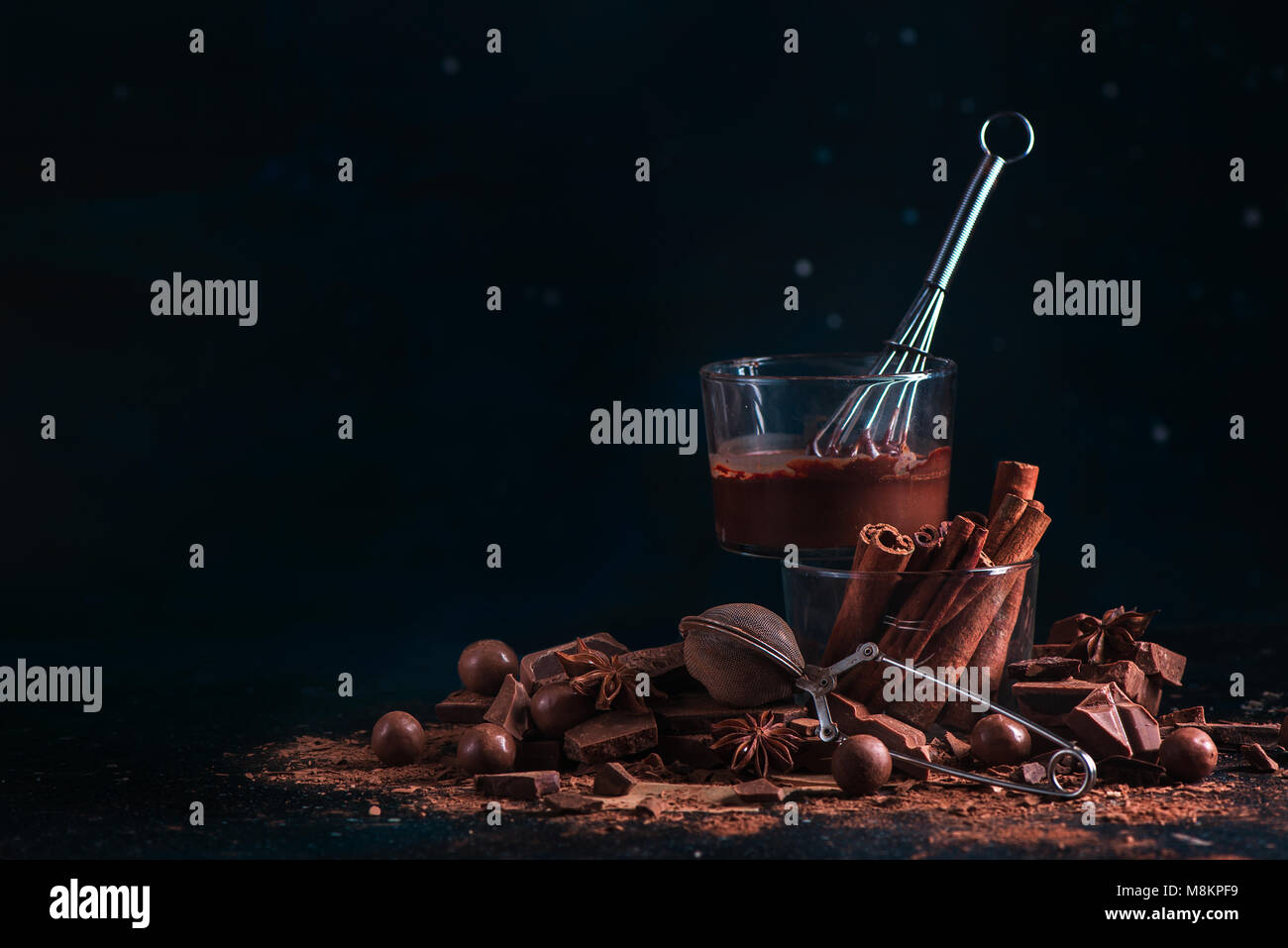 Ingrédients chocolat fait maison sur un fond sombre. Vitrage avec un fouet, la cannelle, casse de pièces en chocolat, poudre de cacao et à l'anis étoile. Dessert co Banque D'Images