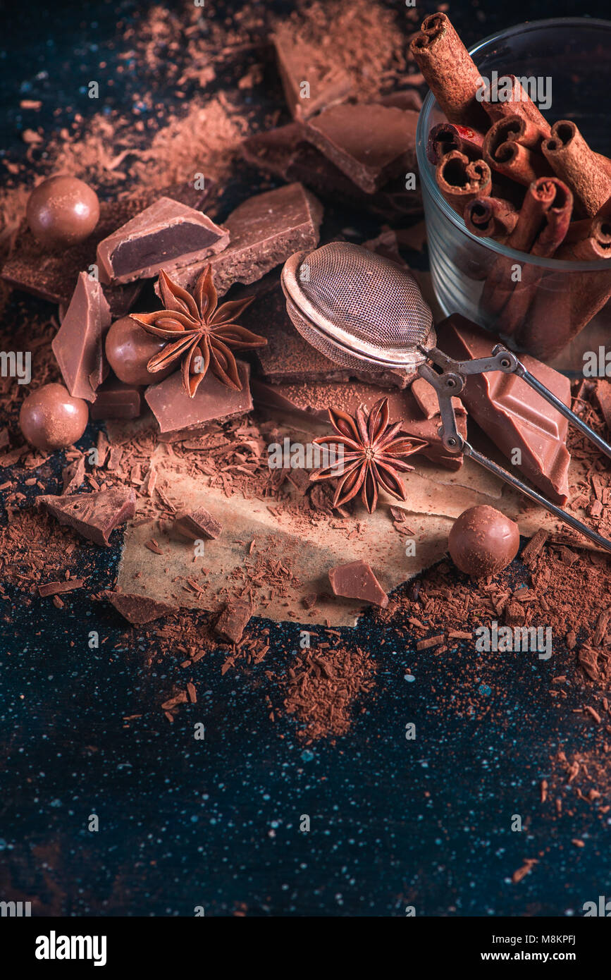 La cannelle dans du verre brisé la guerre avec morceaux de chocolat, poudre de cacao et à l'anis étoile. Concept de cuisine dessert avec copie espace. Chocolat maison ingredie Banque D'Images