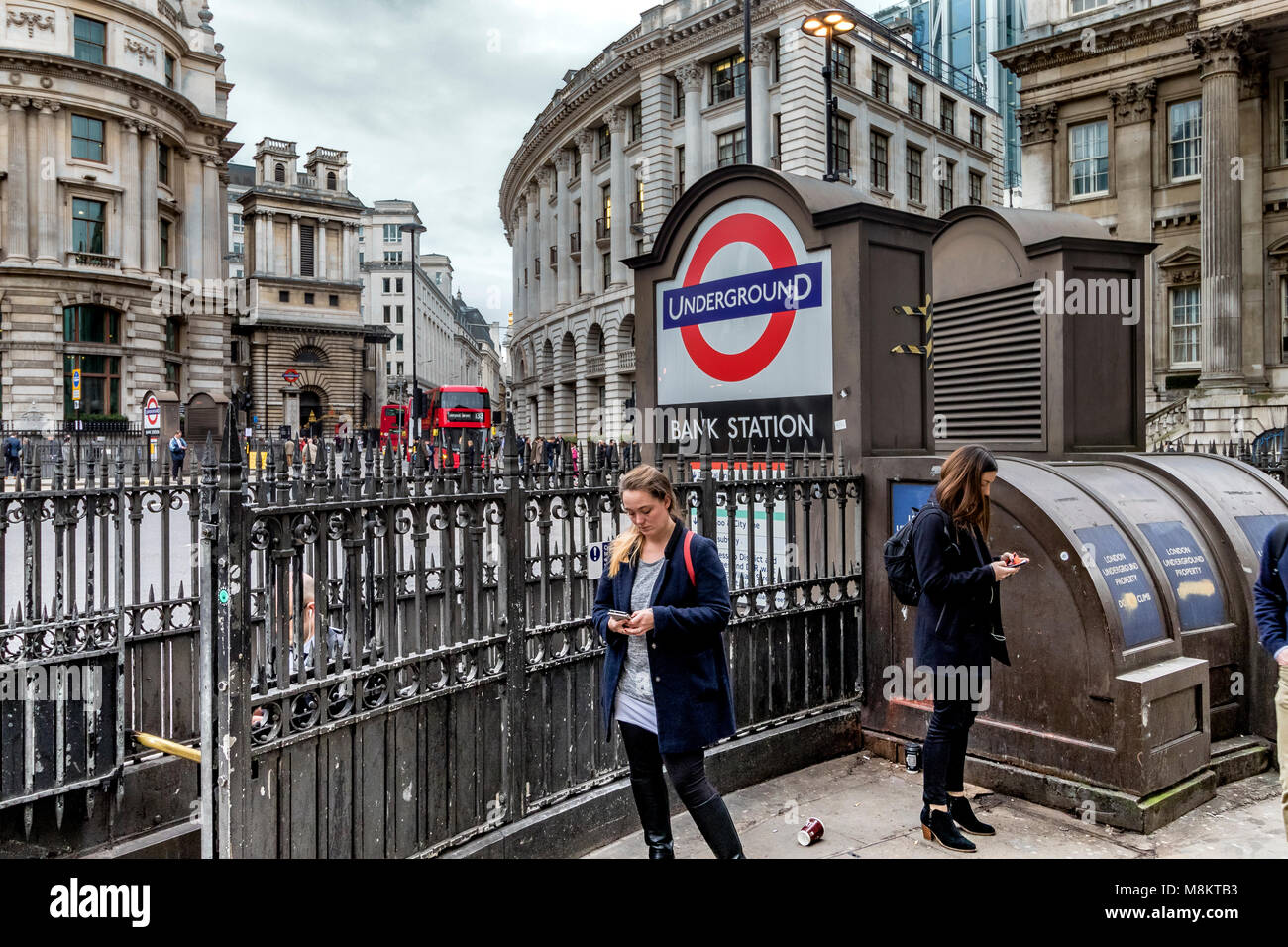 Deux femmes à la recherche de téléphones mobiles à l'extérieur de la station de métro Bank , Princes St , ville de Londres , Royaume-Uni Banque D'Images