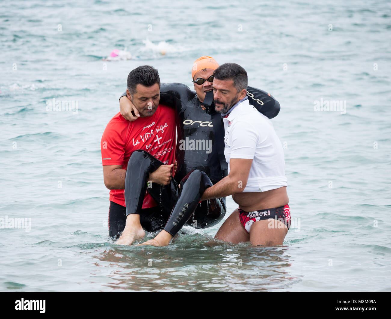 Un triathlète handicapé est aidé hors de l'eau après avoir terminé l'étape de la nage à l'ETU triathlon sprint triathlon coupe européenne sur Gran Canaria Banque D'Images