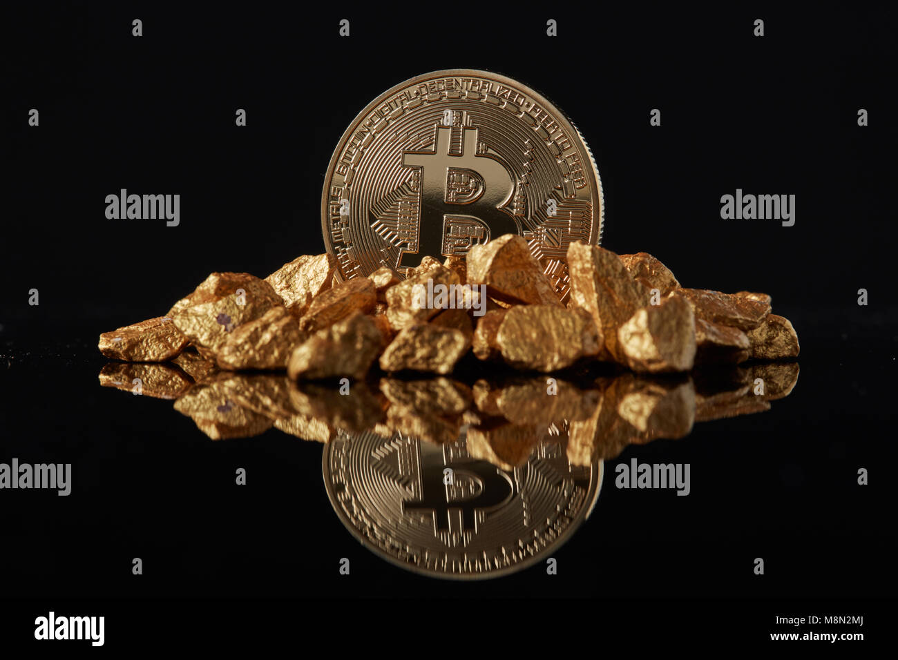 Coin Bitcoin or et butte de l'or sur un fond sombre. Banque D'Images