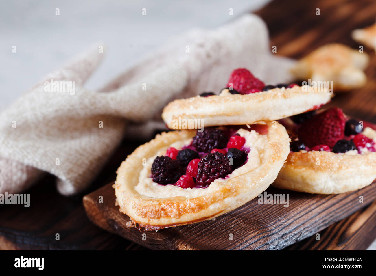 Mini-gâteau au fromage sur la pâte feuilletée aux fruits rouges sur fond de bois foncé Banque D'Images