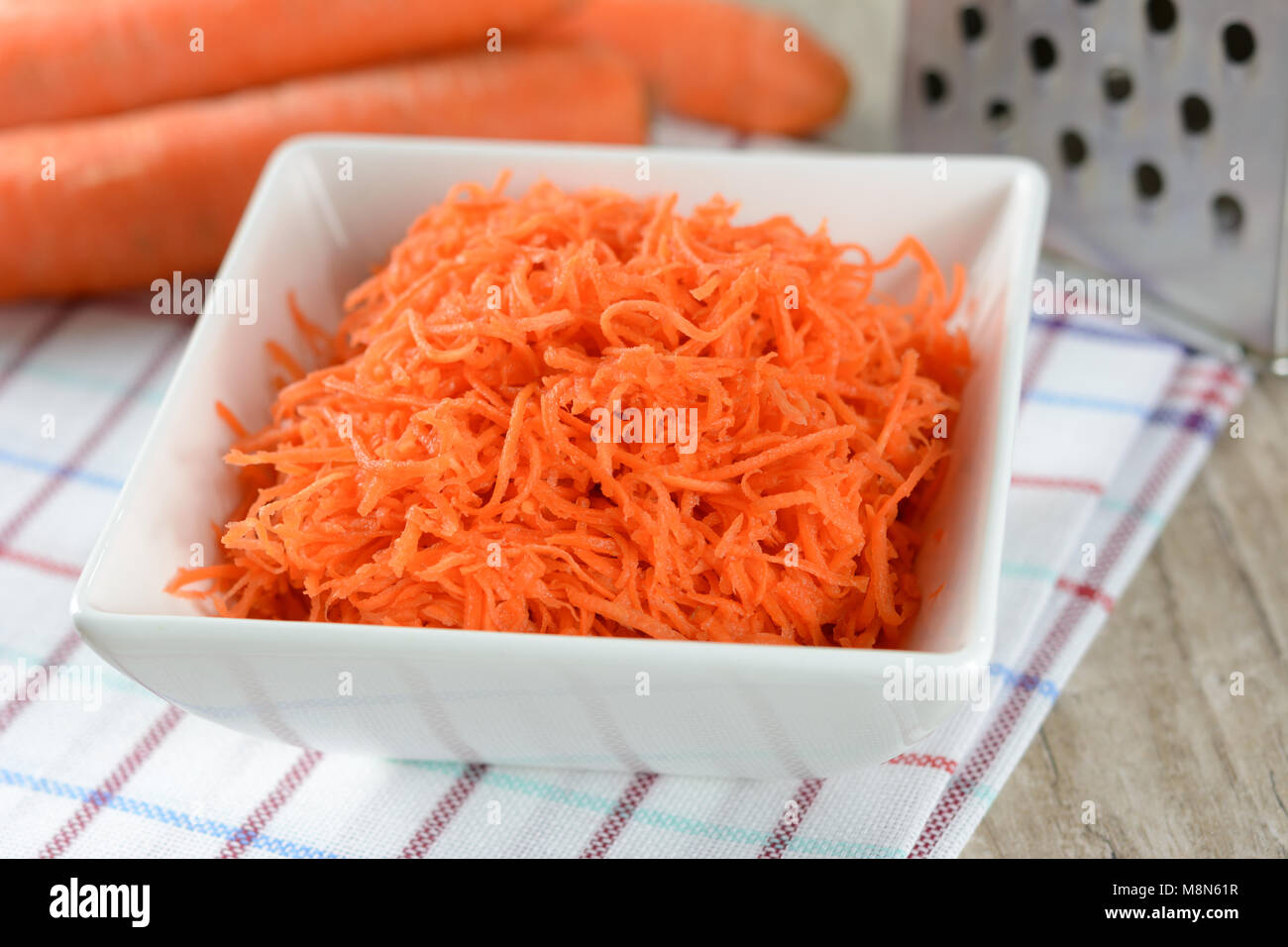 Concept de préparer une salade saine - carottes râpées dans un plateau blanc sur fond de couleurs vives et les carottes. Banque D'Images