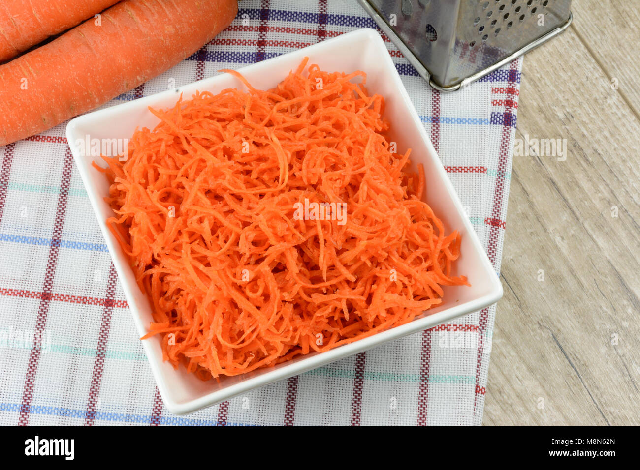 Concept de préparer une salade saine - carottes râpées dans un plateau blanc sur fond de couleurs vives et les carottes. Banque D'Images