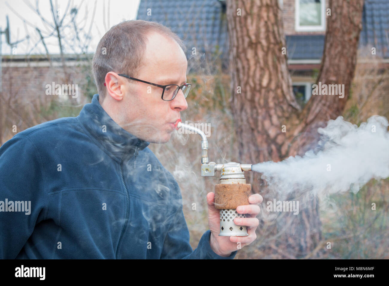 La fumée homme produit en soufflant dans un fumeur. Utilisé pour l'apiculture à maîtriser l'agressivité des abeilles Banque D'Images