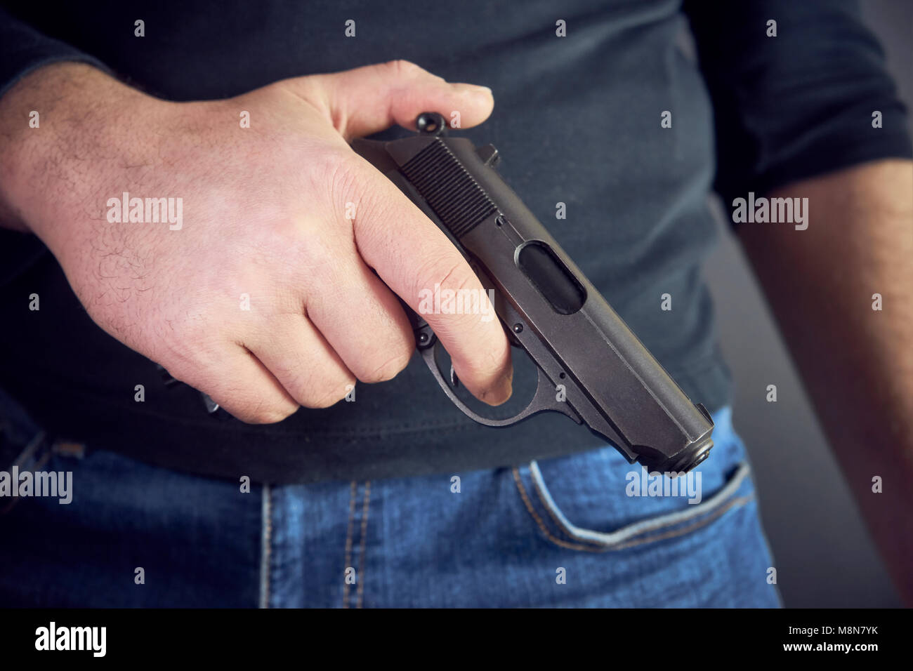 Killer tenant un pistolet lui côté , cropped shot of man holding l'arme à la main. Banque D'Images