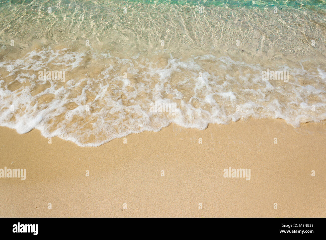Vagues douces avec mousse de bleu océan sur la plage de sable Banque D'Images