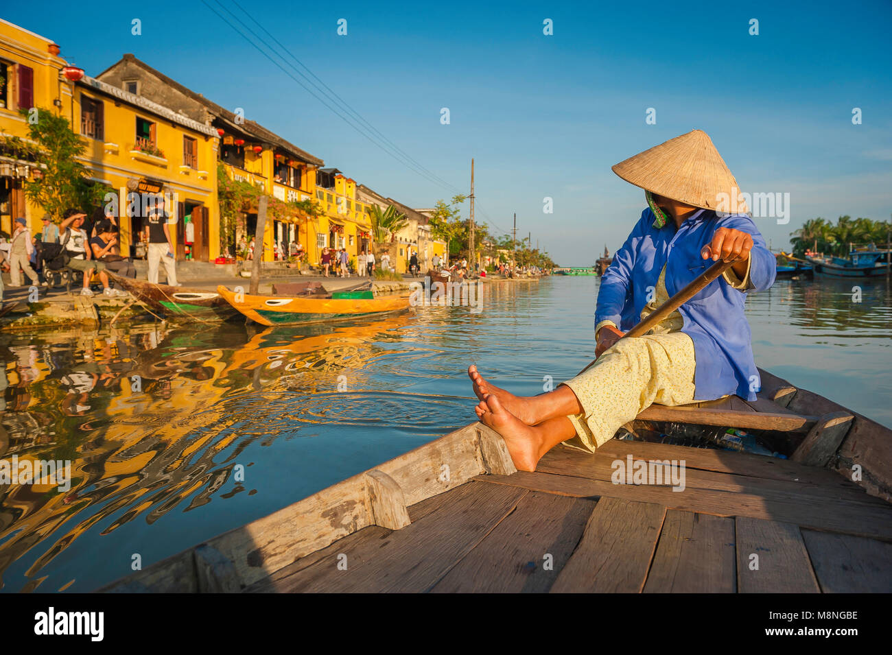 Vietnam tourism couleur, un bateau vietnamien 'lady' dans un chapeau conique glisse le long de la rivière Thu Bon à Hoi An, Vietnam central. Banque D'Images