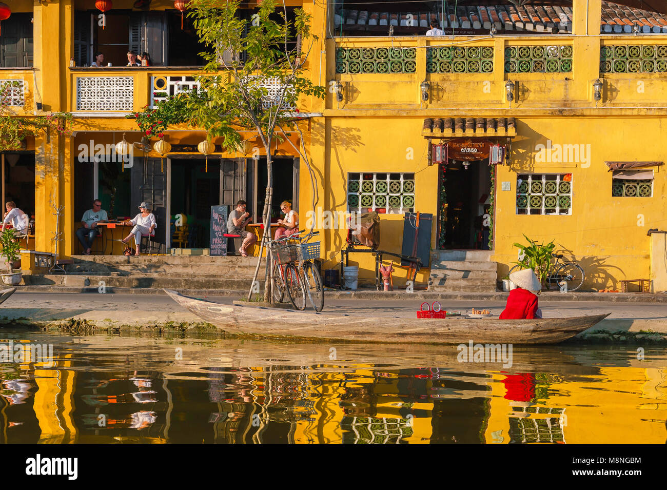 Tourisme du Vietnam, au coucher du soleil le long de la rivière Thu Bon dans la vieille ville de Hoi An, les touristes se détendre dans un café-bar au bord de l'eau, au Vietnam. Banque D'Images