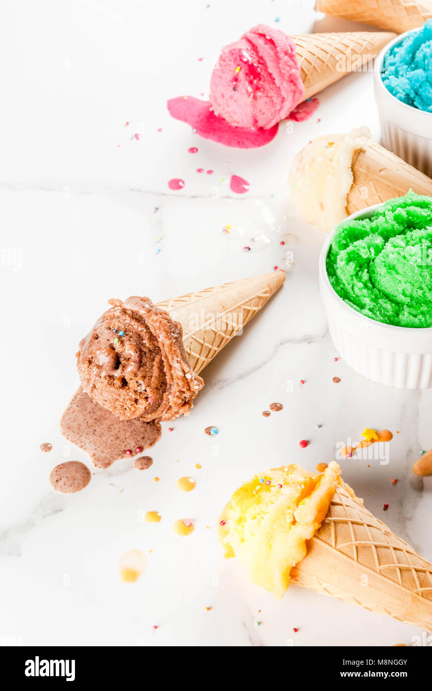 La fonte des glaces faites maison différente de la crème dans des bols et waffle ice cream cones, blanc vanille, orange, rose berry, vert, bleu, chocolat blanc en backg Banque D'Images