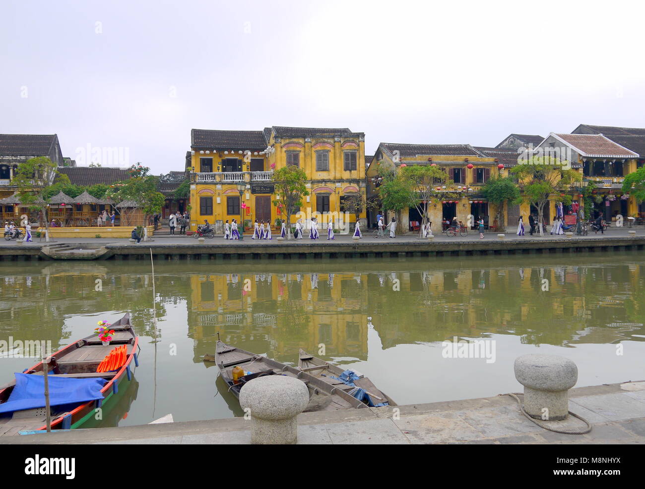 Hoi An, Vietnam - Mars 17, 2018 : Grand groupe de jeunes filles en tenue traditionnelle vietnamienne dans l'ancienne ville de Hoi An avec vue sur les maisons jaune typique Banque D'Images Hoi An, Vietnam - Mars 17, 2018 : Grand groupe de jeunes filles en tenue traditionnelle vietnamienne dans l'ancienne ville de Hoi An avec vue sur les maisons jaune typique Banque D'Images