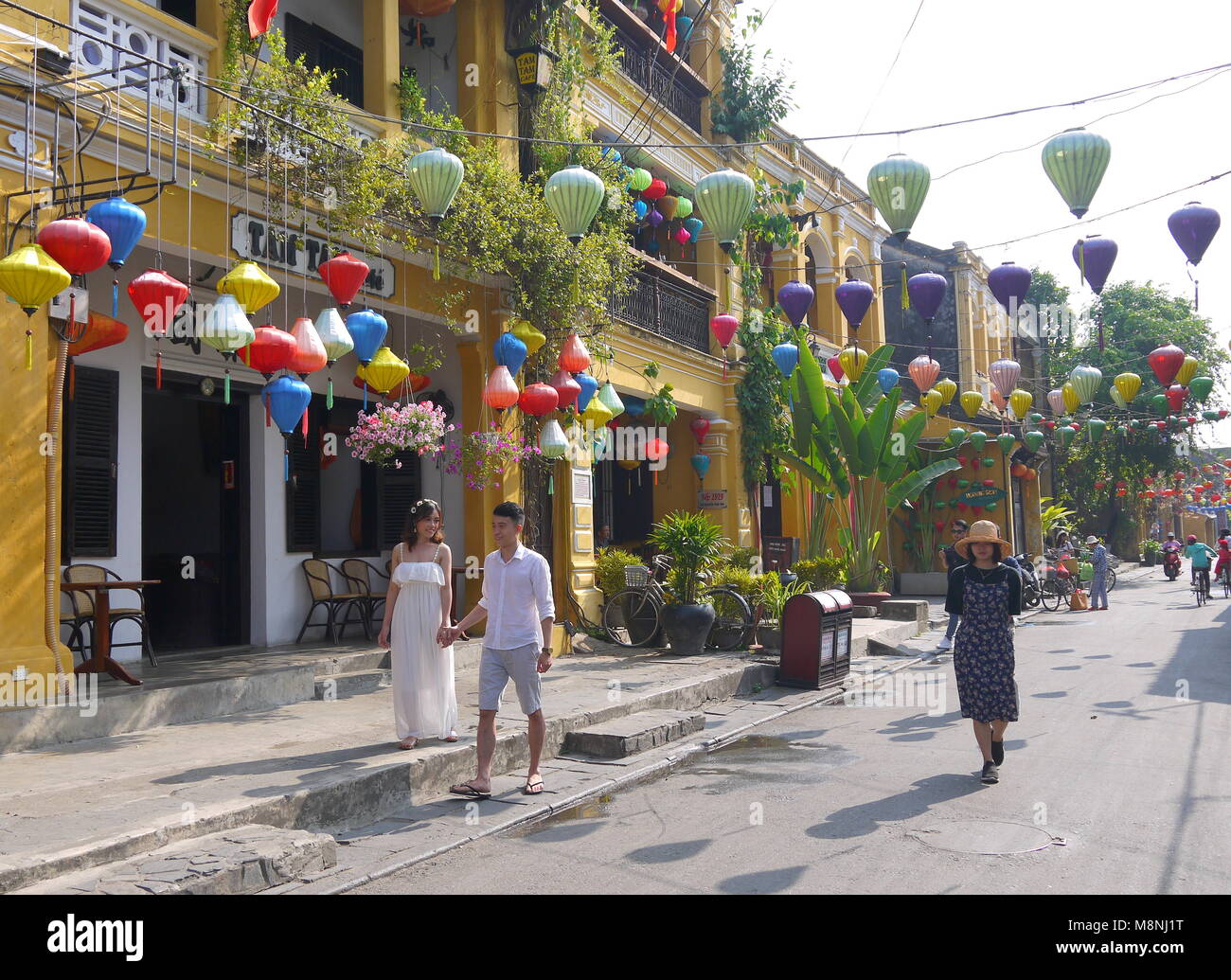 Hoi An, Vietnam - Mars 17, 2018 : Happy couple de touristes sur la rue tôt le matin dans la vieille ville de Hoi An Vietnam avec avis de boutiques Banque D'Images