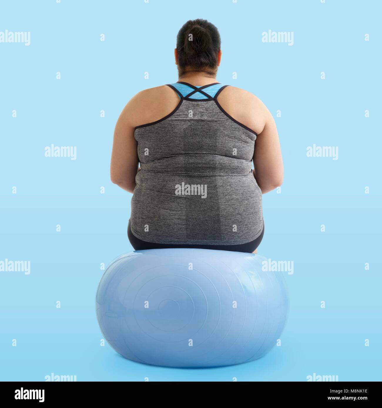 L'excès de femme assise sur une boule d'exercice, vue arrière. Banque D'Images