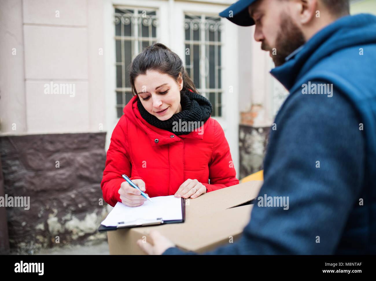 Femme qui reçoit de l'homme livraison de colis à la porte. Banque D'Images