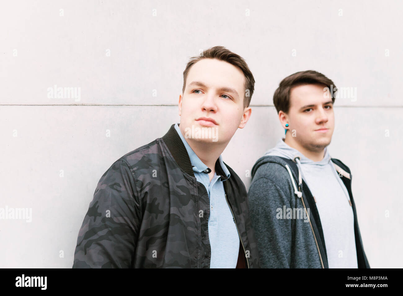 Deux amis adolescents de sexe masculin ou brothers leaning against wall Banque D'Images