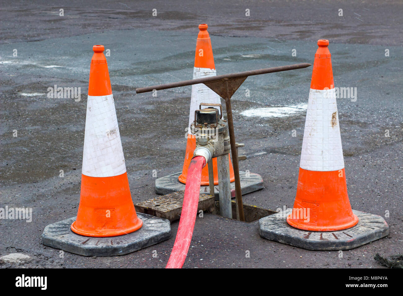 Une série de cônes de signalisation haute visibilité entourant une fontaine d'eau pour des raisons de sécurité alors qu'il est en cours d'utilisation Banque D'Images