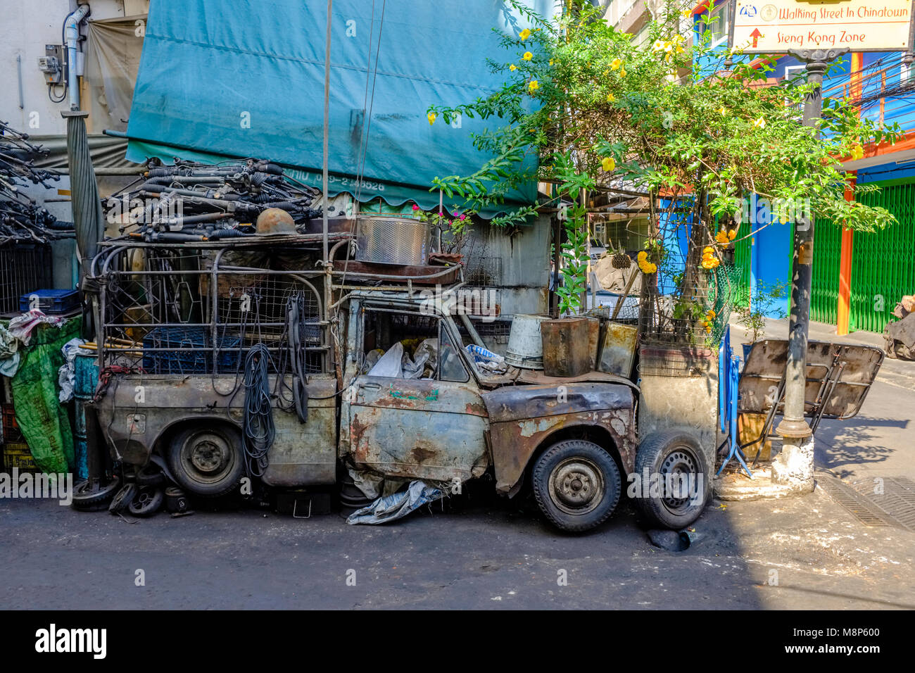 Une voiture accidentée est chargé avec de vieilles pièces de voiture en face d'un garage Banque D'Images