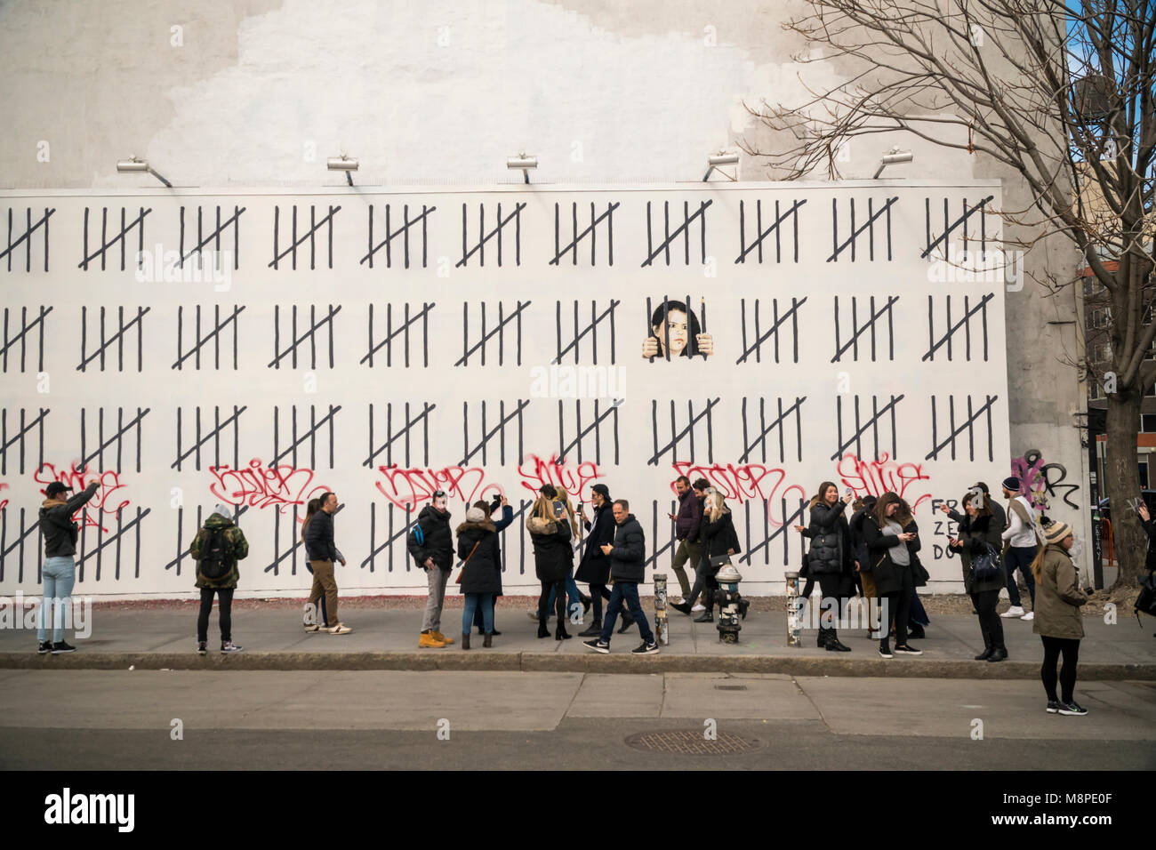 Les amateurs d'art de rue se rendent dans la 'Bowery Mur sur Houston Street, à New York, le Samedi, Mars 17, 2018 pour voir et photographier l'artiste Banksy's collaboration avec l'artiste de rue, Borf. Le travail est un hommage à l'artiste kurde turc emprisonné Zehra Dogan, qui a été arrêté pour la peinture un travail doté d''une ville kurde en ruines après un conflit entre l'armée et rebelles kurdes. Le travail de Banksy, précédemment paru à New York en octobre 2013 lorsqu'il a créé une œuvre par jour pendant un mois son 'residency'. (Â© Richard B. Levine) Banque D'Images