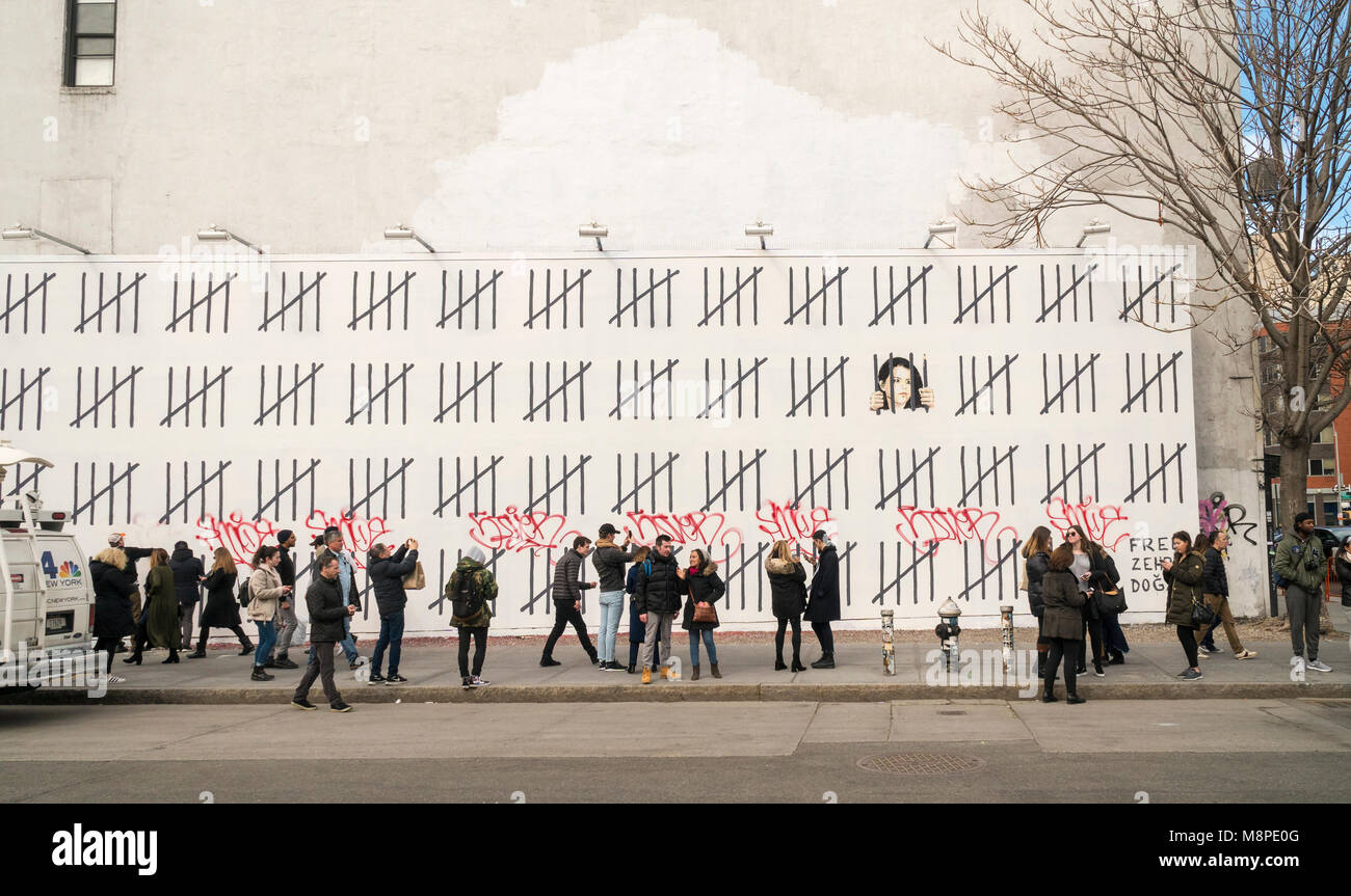 Les amateurs d'art de rue se rendent dans la 'Bowery Mur sur Houston Street, à New York, le Samedi, Mars 17, 2018 pour voir et photographier l'artiste Banksy's collaboration avec l'artiste de rue, Borf. Le travail est un hommage à l'artiste kurde turc emprisonné Zehra Dogan, qui a été arrêté pour la peinture un travail doté d''une ville kurde en ruines après un conflit entre l'armée et rebelles kurdes. Le travail de Banksy, précédemment paru à New York en octobre 2013 lorsqu'il a créé une œuvre par jour pendant un mois son 'residency'. (Â© Richard B. Levine) Banque D'Images