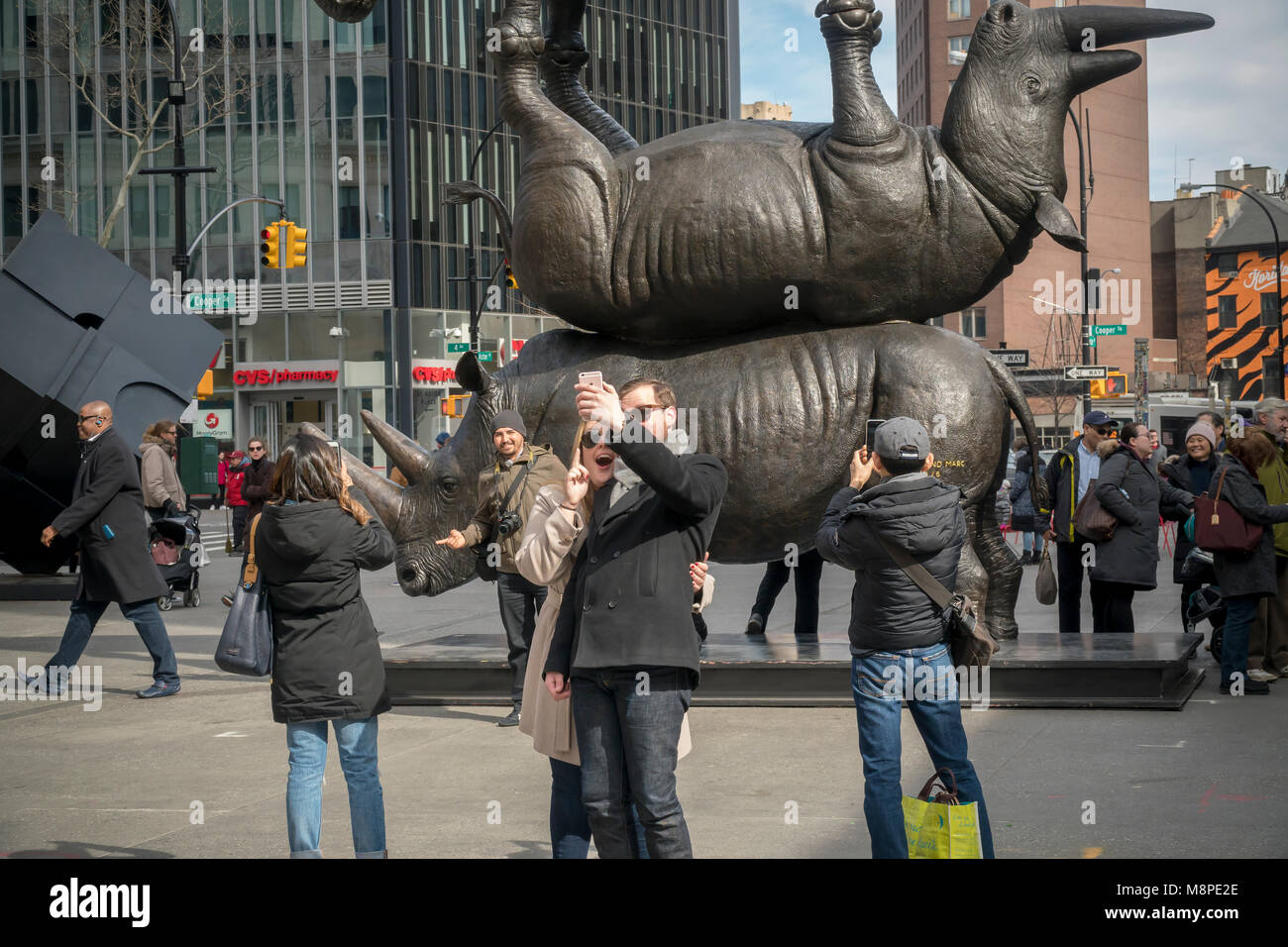 Visiteurs d'Astor Place à New York le Samedi, Mars 17, 2018Voir 'Les trois derniers', un 17-pieds de haut, 7 tonnes de sculpture en bronze des trois derniers rhinocéros blancs du Nord. L'oeuvre de l'artistes connus sous le nom de Gillie et Marc attire l'attention sur la disparition des rhinocéros qui sont actuellement protégés contre les braconniers dans un composé de la faune du Kenya. Le mâle rhino, Soudan, a une faible numération des spermatozoïdes et ses filles Najin et Fatu sont infertiles de sorte qu'il est probable que l'espèce sera bientôt éteintes. Les cornes de rhinocéros sont considérés comme un aphrodisiaque dans certaines cultures, de sorte que l'espèce, et les rhinocéros en général, ont subi le gre Banque D'Images