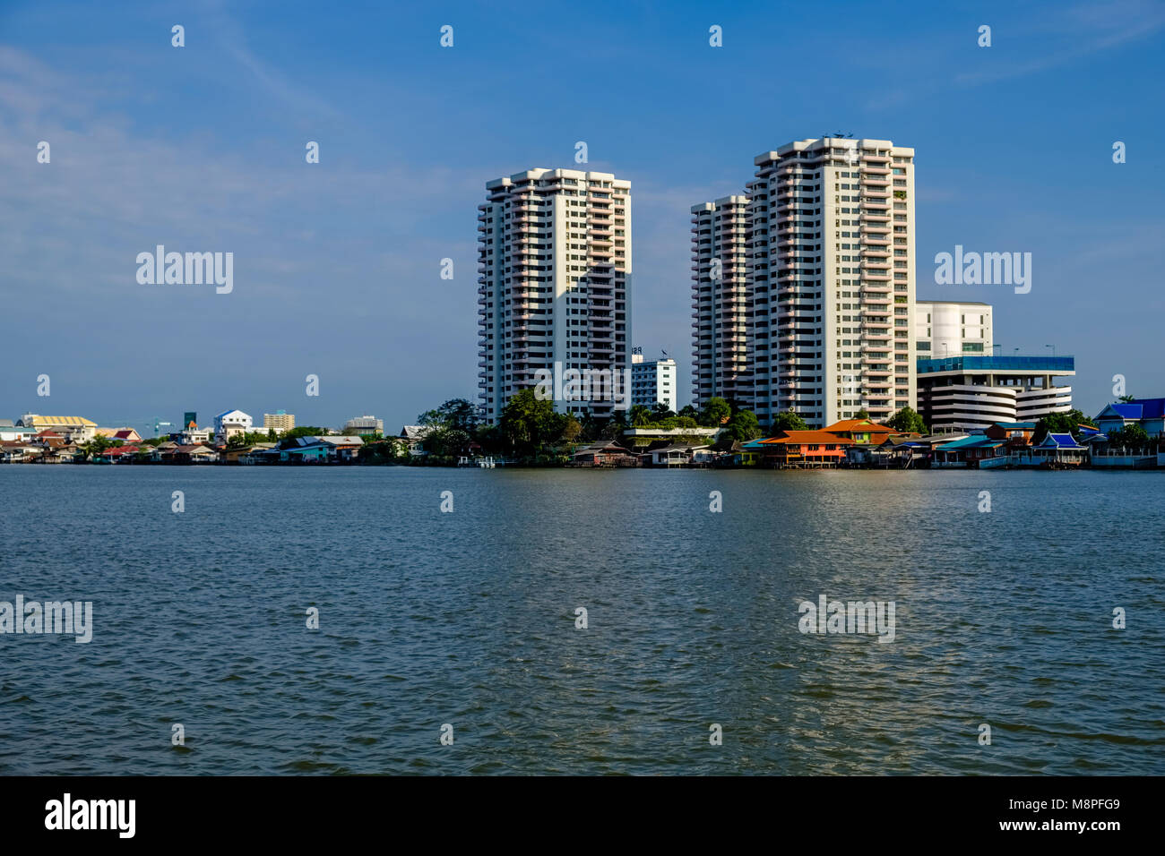 Les maisons sur pilotis et certains immeubles de grande hauteur, vu de l'autre côté de la rivière Chao Phraya Banque D'Images