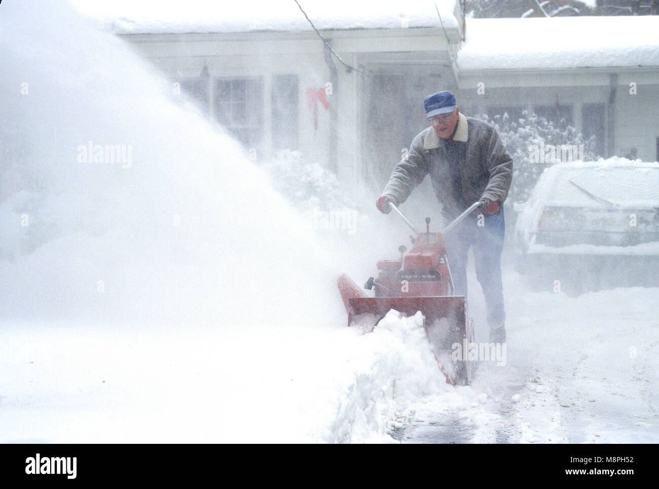 Un homme à l'aide d'une souffleuse à neige dans son allée, pendant une tempête.USA Banque D'Images