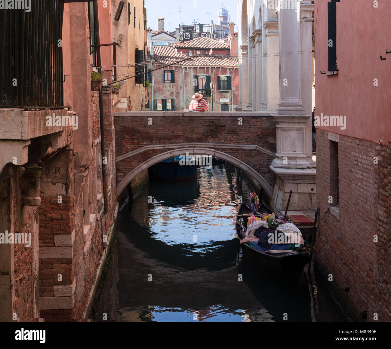 Gondolier attend l'arrivée de touristes sur le pont d'un petit canal à Venise Banque D'Images