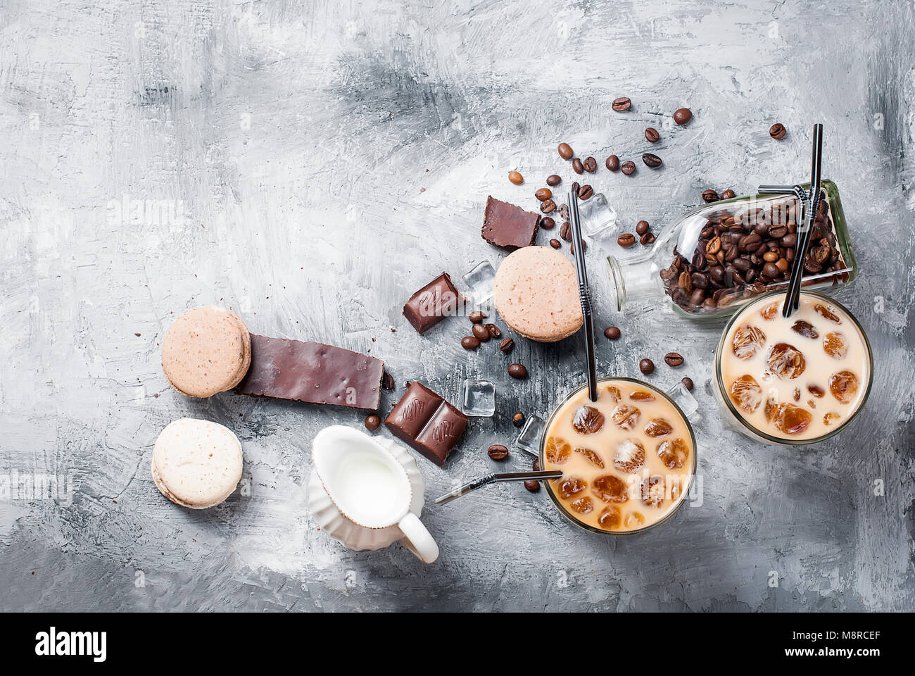 Glace café en verre, macarons,, morceaux de chocolat et les grains de café sur une table gris , vue d'en haut, copy space Banque D'Images