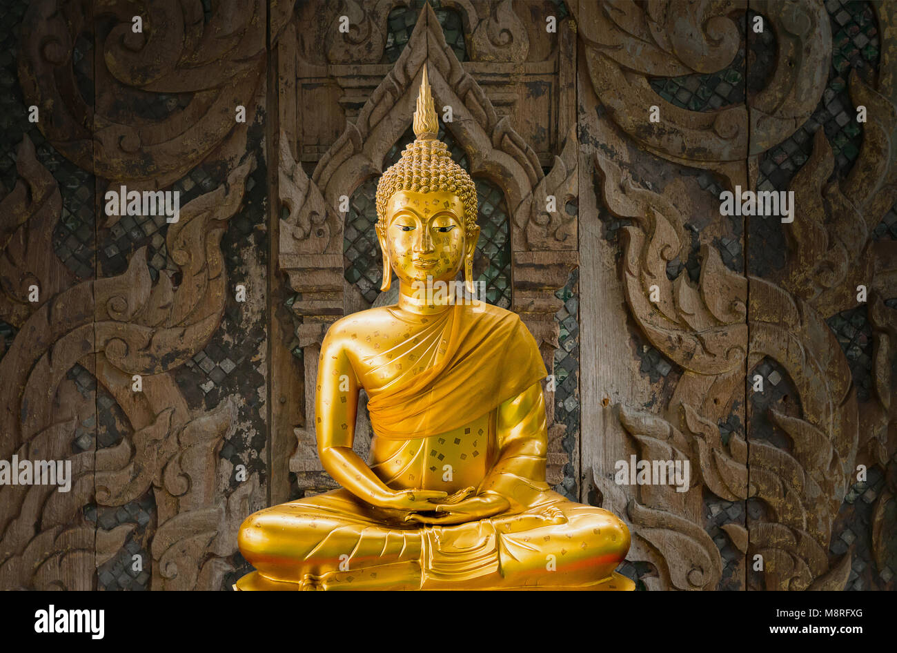 Ancienne statue de Bouddha en or avec la sculpture sur bois en arrière-plan Banque D'Images
