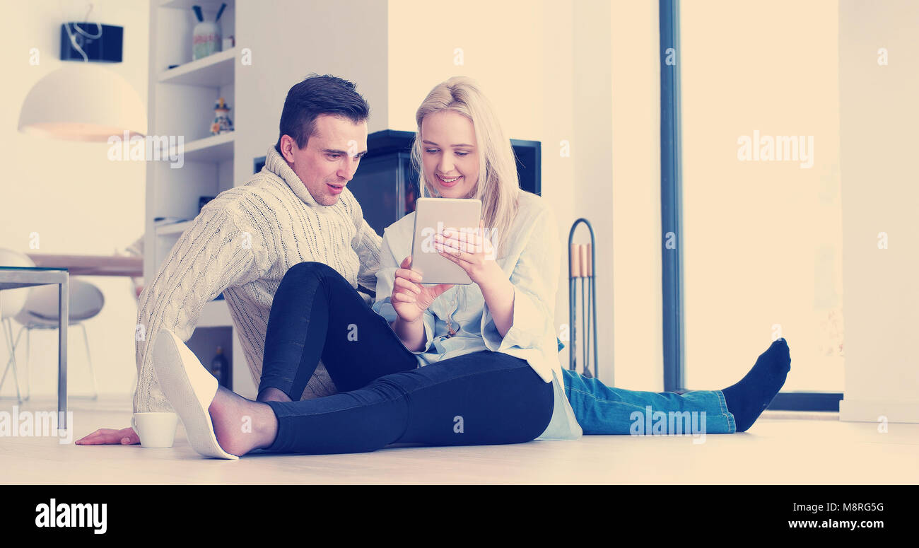 Jeune couple assis sur le plancher et à l'aide d'interent sur tablette numérique Banque D'Images