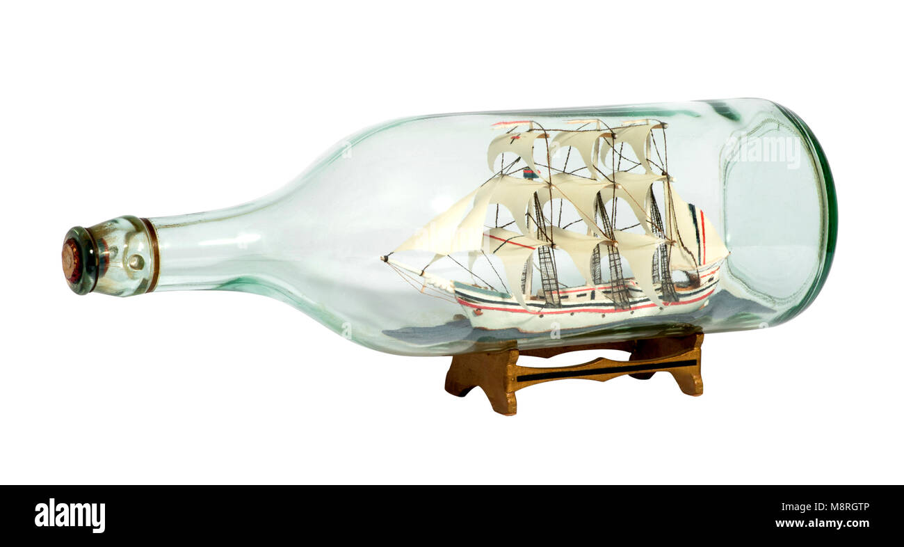Modèle d'un navire à voile entièrement gréé de voiles dans une bouteille en verre clair sur un petit support en bois isolé sur blanc Banque D'Images